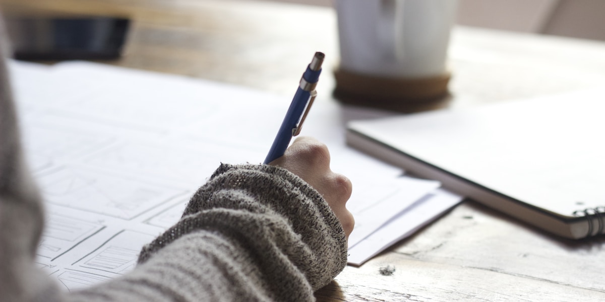 A hand writing equations in a notebook