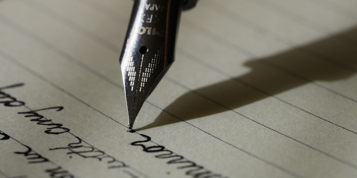 A person writing with a pen, working through careful calculations